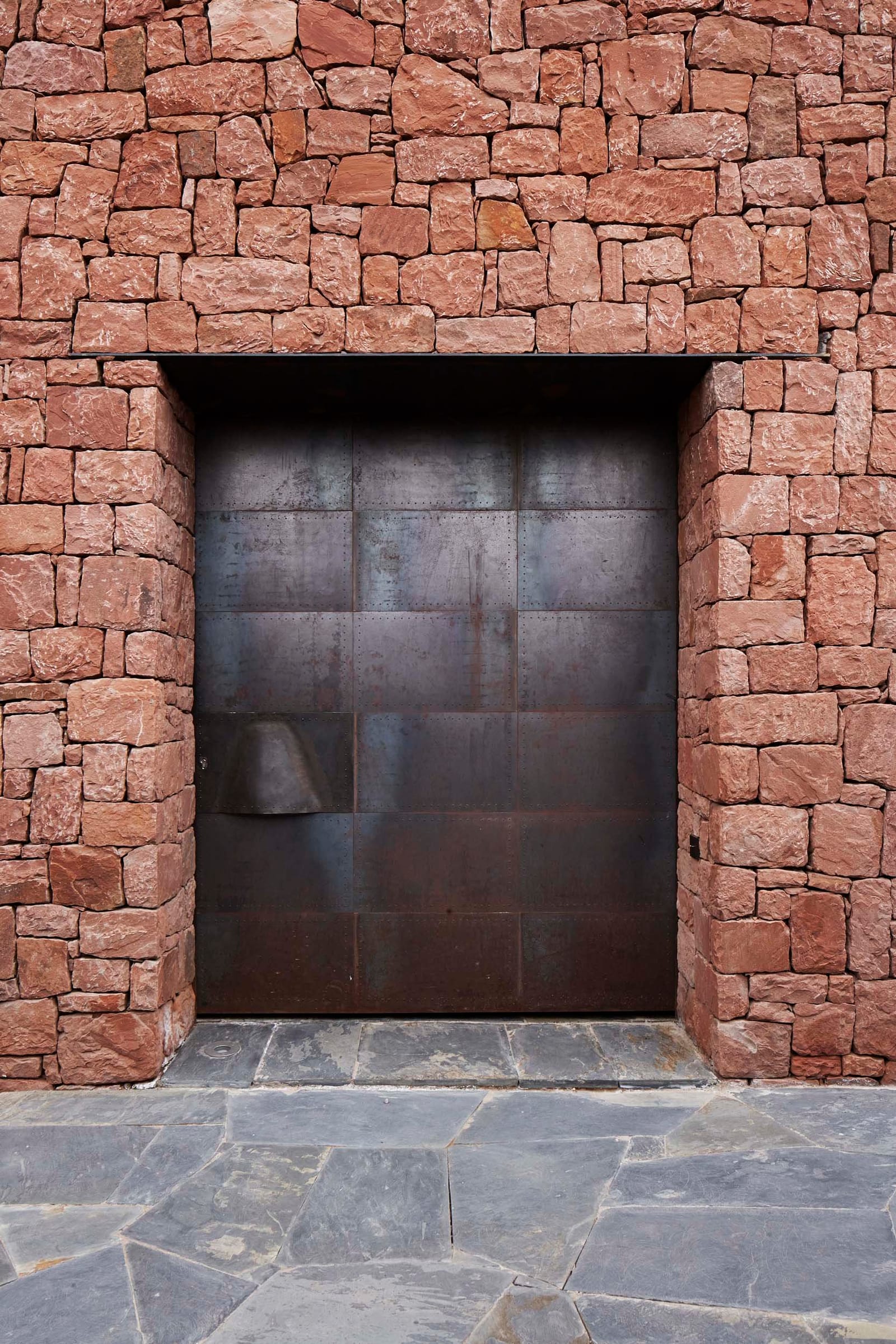 Burnished steel door set in Villa E's stone wall